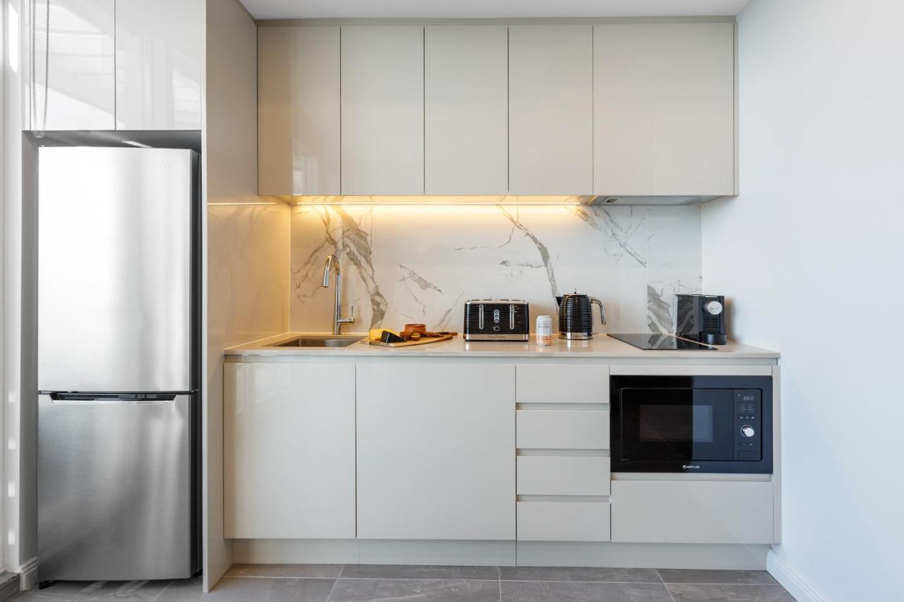 Meriton Suites Bondi Junction Sídney Exterior foto The photo shows a modern kitchen featuring a sleek design. It includes light-colored cabinetry with a smooth finish and upper cabinets that blend seamlessly with the wall. The countertop is made of a light stone, complementing the overall aesthetic. 